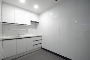 a white kitchen with white cabinets and a sink at WA Hotel in Busan