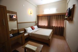 Kleines Zimmer mit einem Bett und einem TV in der Unterkunft Haksons Residency in Mananthavady