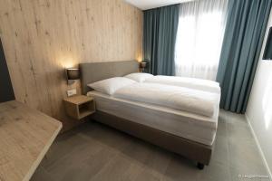 1 dormitorio con 1 cama grande y ventana en Bergresort Gerlitzen by ALPS RESORTS en Treffen