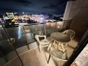 balcón con mesa, sillas y vistas al perfil urbano en Ganclik apartment by Baku housing en Bakú