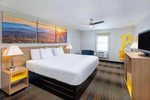 a hotel room with a bed and a flat screen tv at Days Inn by Wyndham Holladay in Holladay
