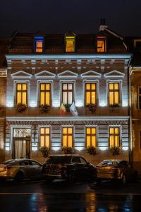 oświetlony budynek z samochodami zaparkowanymi przed nim w obiekcie CASA CHITIC - HOTEL & RESTAURANT- Str Nicolae Balcescu 13 w Braszowie