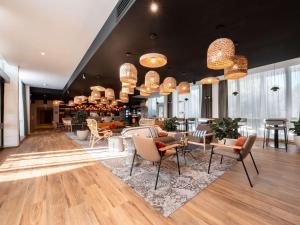 a lobby with chairs and tables and chandeliers at Novotel Chartres in Chartres