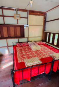 a bed in a room with red sheets and pillows at Dragon Pearl Beach Resort in Kota Belud