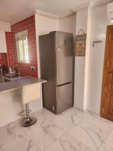 uma cozinha com um frigorífico de aço inoxidável e um balcão em Villa San Jose II Townhouse em Cabo Roig
