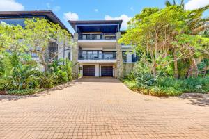a brick driveway in front of a house with trees at Phezulu Villas 2, Zimbali Estate in Ballito