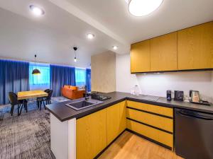 a kitchen with yellow cabinets and a dining room at Hotel Ibis Krakow Centrum in Kraków