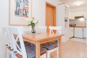 une table à manger avec des chaises blanches et un vase de fleurs dans l'établissement An der Aue 9a, Wohnung 9, à Dahme