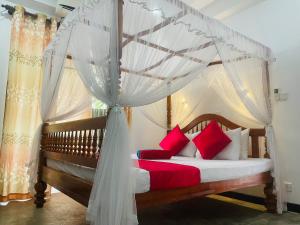 Cinnamon City في هيكادوا: غرفة نوم مع سرير المظلة مع الوسائد الحمراء والبيضاء