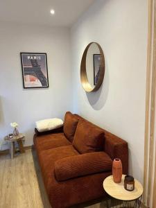 a living room with a brown couch and a mirror at Logement cosy entier in Le Kremlin-Bicêtre