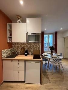 a kitchen with white cabinets and a table and a dining room at Logement cosy entier in Le Kremlin-Bicêtre