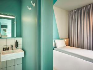 a small bathroom with a sink and a bed at ibis budget Epinal in Épinal