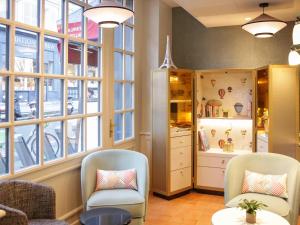 a room with two chairs and a table and windows at Mercure Paris Notre Dame Saint Germain des Prés in Paris