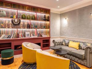 a living room with a couch and chairs and books at Mercure Paris Notre Dame Saint Germain des Prés in Paris
