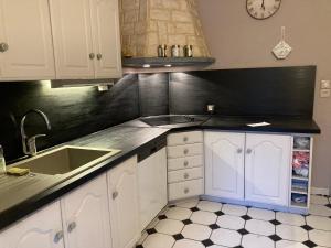 uma cozinha com armários brancos e um lavatório em Ma demeure em Le Gué-de-Longroi