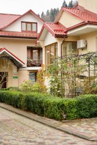 a house with a hedge in front of a street at Петрос Family Hotel in Yaremche