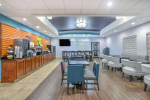 a restaurant with tables and chairs and a counter at La Quinta by Wyndham Tulsa Airport / Expo Square in Tulsa