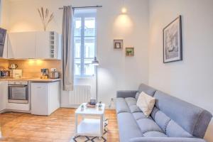 een woonkamer met een blauwe bank en een keuken bij L'Esméralda en coeur de ville in Périgueux