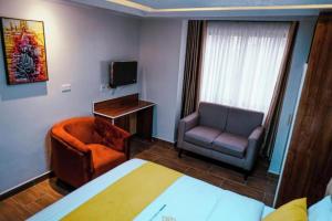 um quarto de hotel com uma cama e uma cadeira e uma televisão em Barre Hotel em Nairobi