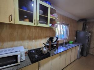 a kitchen with a stove and a microwave at Entire 3 Bedroom Bungalow - Home away from home in Lagos