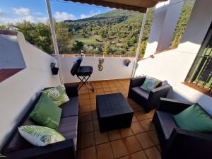 a balcony with couches and a view of a mountain at Aptm Dayma Sierra junto al río Majaceite. in Benamahoma