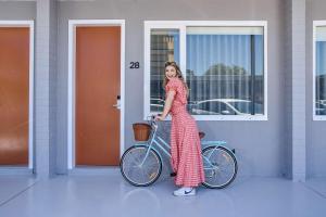 Młoda dziewczyna stoi obok roweru. w obiekcie HotelMOTEL Adelaide w mieście Adelaide