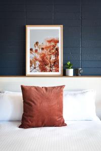 a picture frame above a bed with a red pillow at HotelMOTEL Adelaide in Adelaide