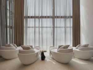 SO/ Uptown Dubai في دبي: ثلاثة كراسي بيضاء في غرفة مع نوافذ كبيرة