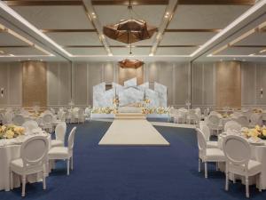 un salón de banquetes con mesas y sillas blancas y un escenario en SO/ Uptown Dubai, en Dubái