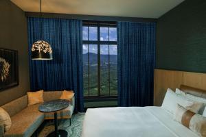 a hotel room with a bed and a couch and a window at Cloudland at McLemore Resort Lookout Mountain, Curio Hilton in Rising Fawn
