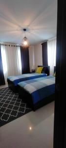 two beds in a bedroom with blue sheets and yellow pillows at Bloomfields Residences in Balintiouac