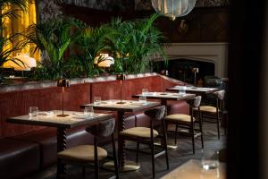 une rangée de tables dans un restaurant avec des plantes dans l'établissement Lanelay Hall Hotel & Spa, à Hensol