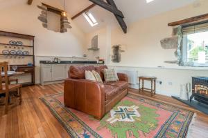 a living room with a leather couch and a kitchen at Stabal-Byrdir in Dyffryn