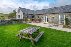 a wooden picnic table in front of a stone house at Stabal-Byrdir in Dyffryn