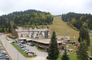 a large building with cars parked in a parking lot at Ski Mont Apartment Jahorina in Jahorina