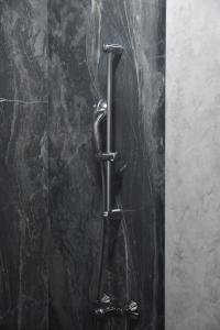 eine Dusche aus schwarzem Marmor mit einer Metallstange in der Unterkunft Hotel Building Stefan Resort I in Mamaia Nord – Năvodari