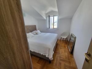 a bedroom with a white bed and a window at Beach Spot Apartments in Makarska