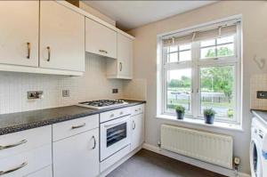 una cocina con armarios blancos y una ventana en The Wickets - 2 bedroom apartment overlooking cricket club, en Marton