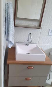 a bathroom with a white sink on a wooden counter at Apto Aviação com Ar-Condicionado in Praia Grande