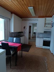 a kitchen with a table with a red table cloth at Aurinko in Varkaus