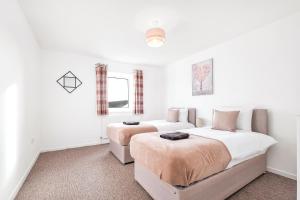 Duas camas num quarto com paredes brancas em Spacious house with 8 beds - convenient location - Whitwell em Peterborough