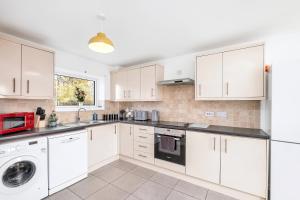 uma cozinha com armários brancos e uma máquina de lavar e secar roupa em Spacious house with 8 beds - convenient location - Whitwell em Peterborough