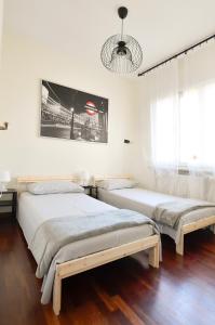 2 letti in una camera con pareti bianche e pavimenti in legno di Il Villino di Monic a Pisa