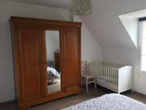 ein großer Holzschrank in einem Schlafzimmer mit Kinderbett in der Unterkunft Gîte en pleine nature au coeur du silence in Laviron