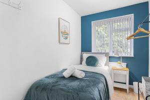 a bedroom with a bed with a blue wall at Stylish Pad Near Heathrow Airport in West Drayton