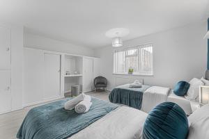 a white room with two beds with towels on them at Stylish Pad Near Heathrow Airport in West Drayton