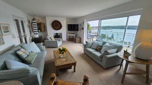 a living room with couches and a view of the water at Fiddlers Green in Saint Mawes