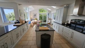 a large kitchen with white cabinets and black counter tops at Fiddlers Green in Saint Mawes