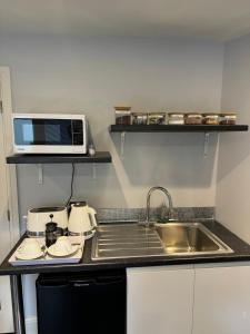 a kitchen with a sink and a microwave at Thistle Lodge - Quiet Garden lodge with off road parking in Hemel Hempstead