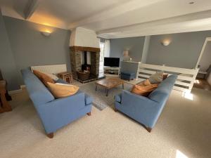 a living room with two blue chairs and a fireplace at Crugsillick Court in Veryan